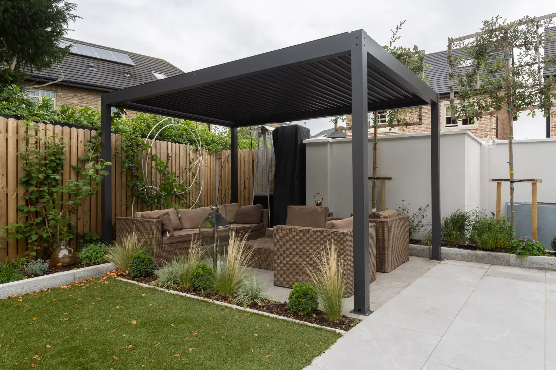 Modern louvered pergola over a patio seating area in a landscaped backyard